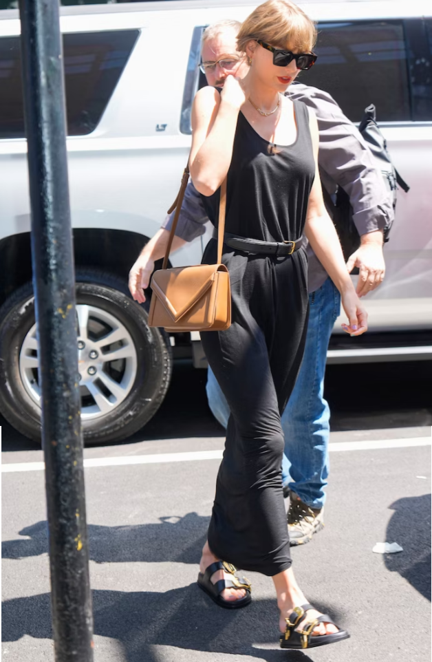 Taylor Swift mặc một chiếc váy maxi thun, màu đen, thắt lưng bằng da ở eo để tạo điểm nhấn. Phụ kiện là chiếc túi đeo chéo của Mansur Gavriel màu camel và mang sandal Birkenstock. Taylor Swift mặc một chiếc váy maxi thun, màu đen, thắt lưng bằng da ở eo để tạo điểm nhấn. Phụ kiện là chiếc túi đeo chéo của Mansur Gavriel màu camel và mang sandal Birkenstock.