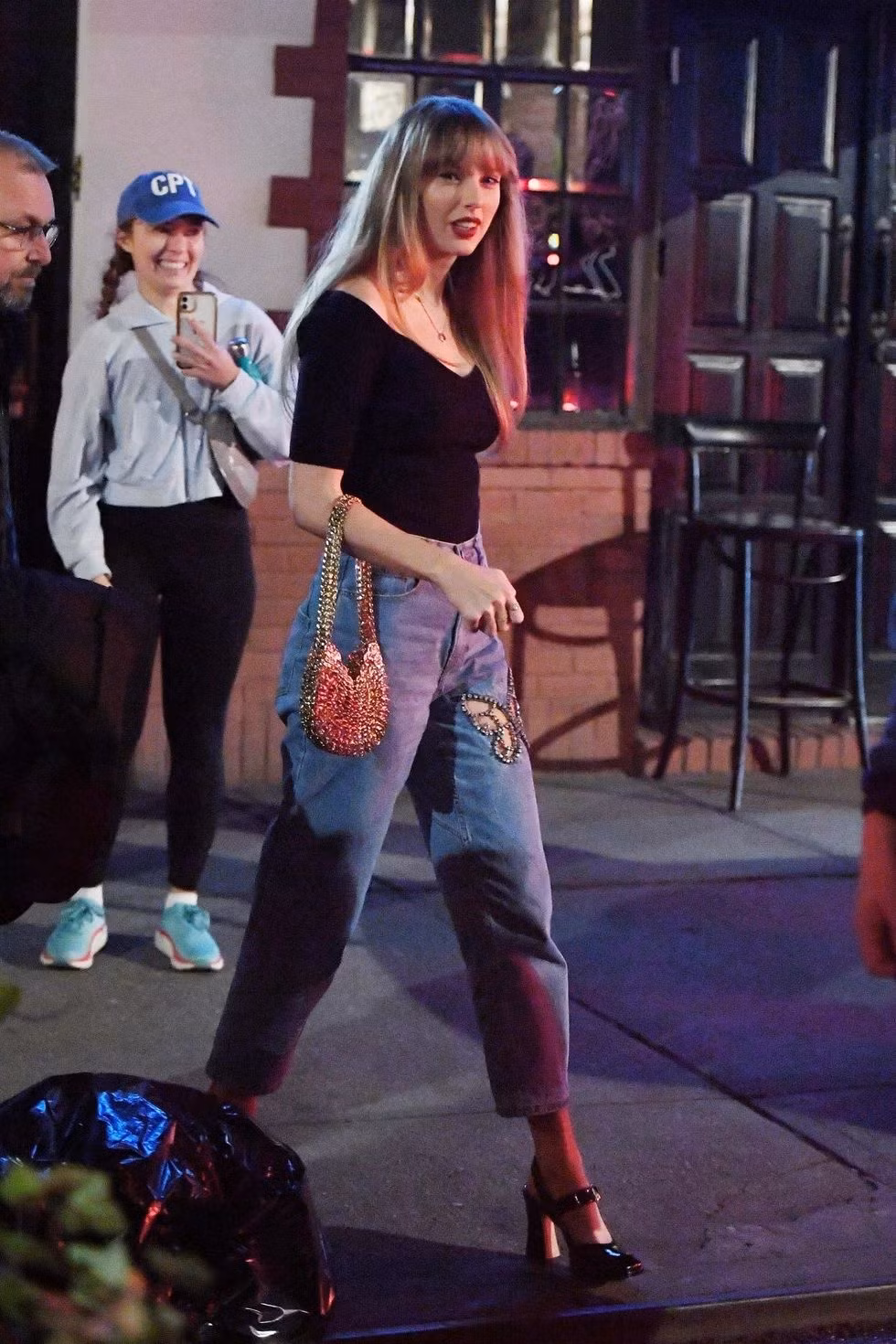 Taylor mặc một chiếc quần jean Area có đường cắt hình con bướm, đính lấp lánh ở đùi, mặc cùng áo thun đen đơn giản và một chiếc túi mini Paco Rabanne màu bạc.