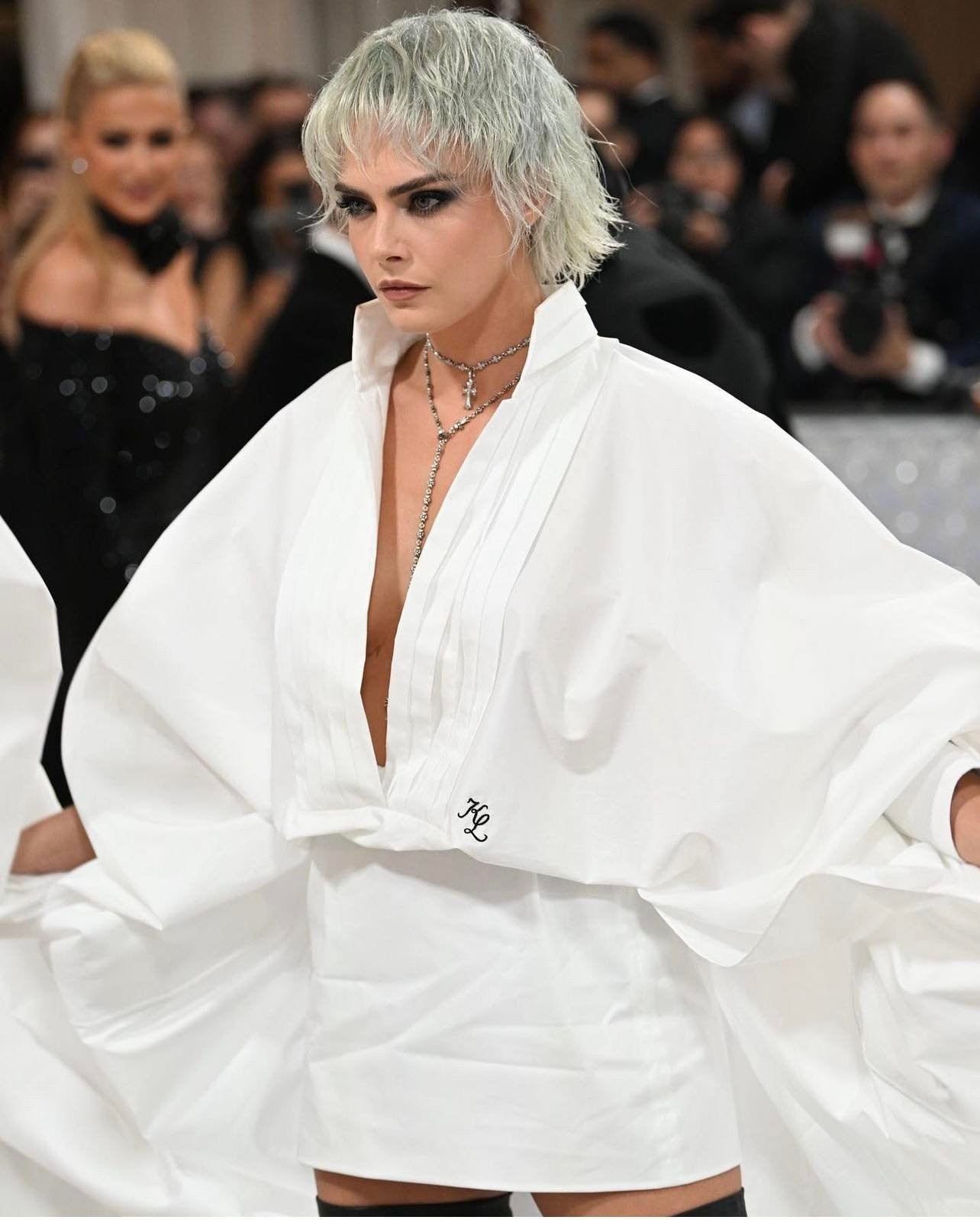 Thật không uổng công sinh thời Karl Lagerfeld cưng chiều Cara Delevingne đến thế, ai lại có thể mặc sơ mi trắng cách điệu mà lại lộng lẫy, hoành tráng pha lẫn trang nghiêm thế này không?! Cô mặc đúng thiết kế của nhà mốt mang tên ông, chữ KL viết tắt trên eo áo.