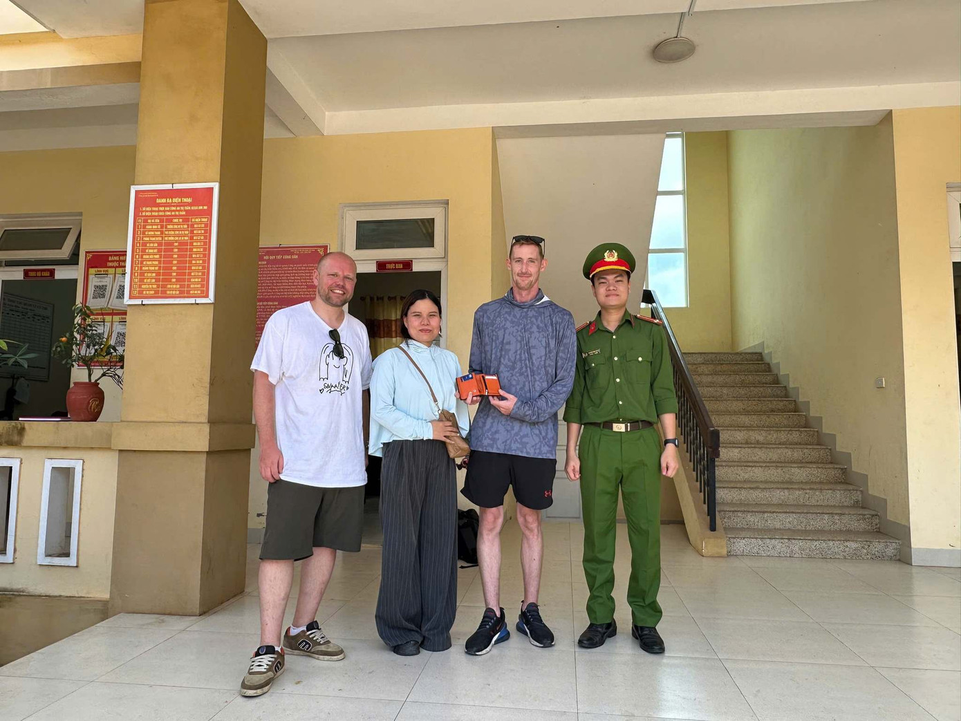 Cô giáo Hồ Thị Khiếp cùng đại diện Công an thị trấn Khe Sanh trả lại tài sản cho du khách người Anh. Ảnh: CAKS