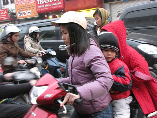 Một em bé ngủ gật khi ngồi sau xe của mẹ về nhà trong giờ cao điểm