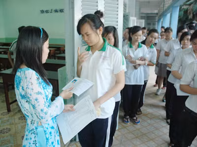 Giám thị kiểm tra giấy tờ của thí sinh trước khi vào thi. Ảnh: Quang Phương