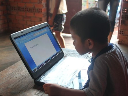 Bé vừa gõ chữ vào máy tính vừa đọc. Ảnh: Chế Bắc