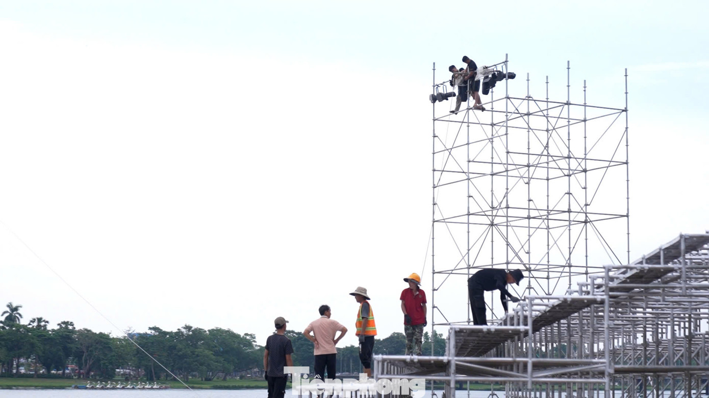 Hình ảnh công nhân đang hoàn thiện sân khấu nổi bên bờ sông Hương.
