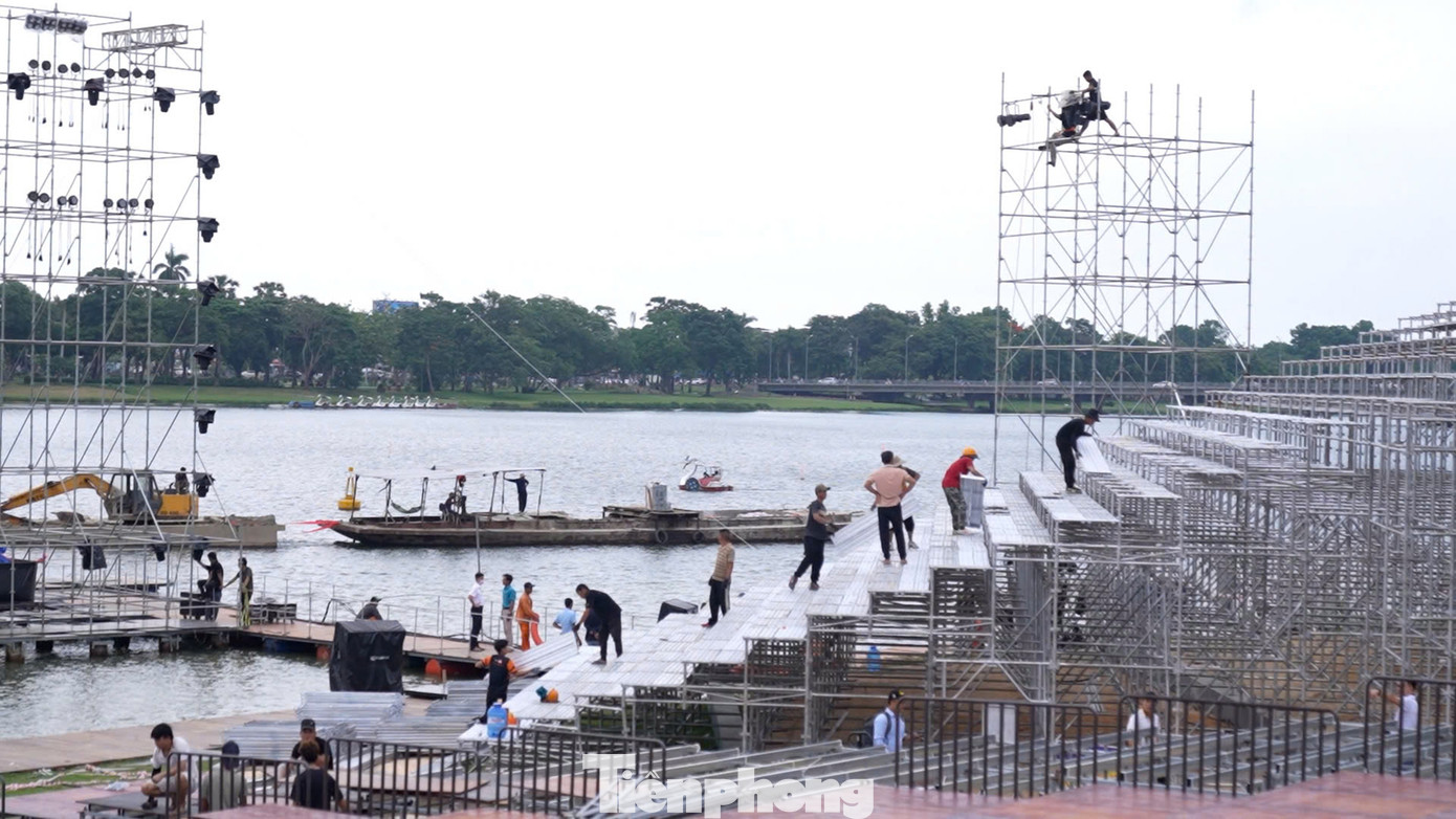 Hình ảnh công nhân đang hoàn thiện sân khấu nổi bên bờ sông Hương.