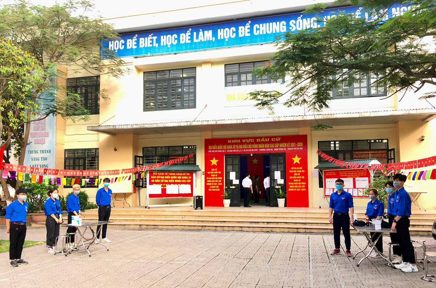 Thanh niên tình nguyện trang bị sẵn sàng khẩu trang, kính chống giọt bắn, máy đo nhiệt độ, nước sát khuẩn để đón tiếp người dân đến địa điểm bầu cử.