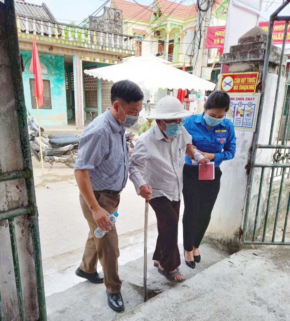 Bóng áo xanh của thanh niên tình nguyện hỗ trợ người dân tham gia bầu cử.