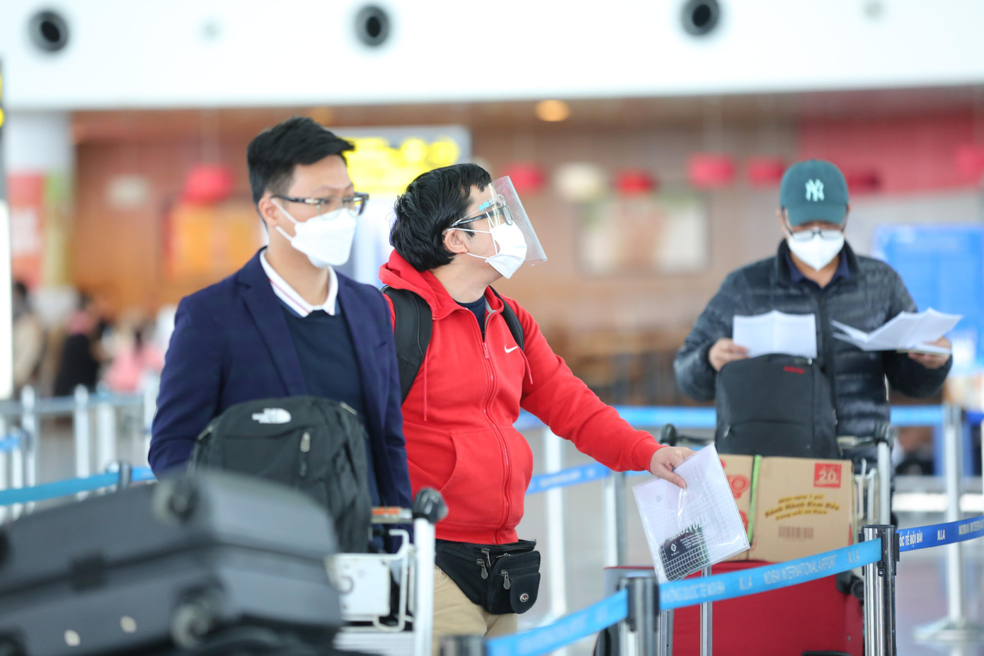 Một số hành khách cẩn thận đeo mũ chống giọt bắn trong lúc đợi làm thủ tục check-in.