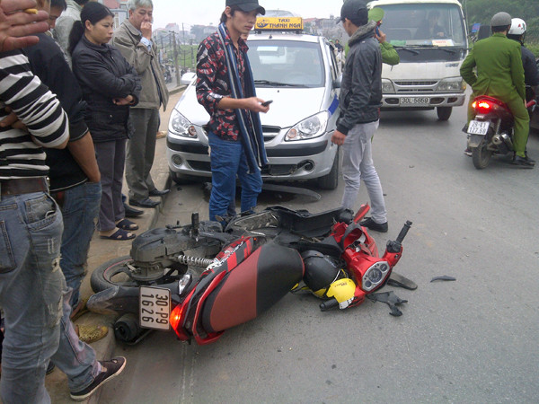 Xe máy 'kẹp 3' đi hết phần đường của chiếc taxi. Ảnh: Đ.H Xe máy 'kẹp 3'