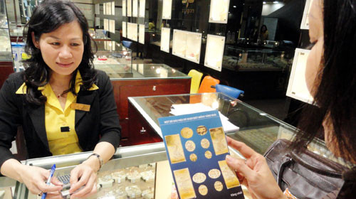 Khách hàng xem cách phân biệt vàng SJC thật và giả tại một tiệm vàng. Ảnh: THANH ĐẠM (Tuổi Trẻ)