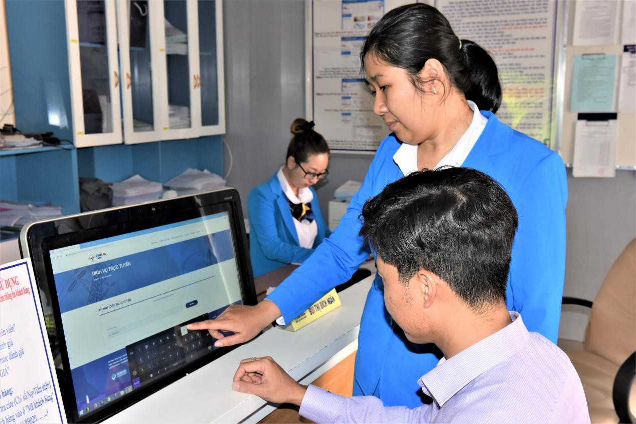 Nhân viên Công ty Điện lực Bình Thuận hướng dẫn khách hàng sử dụng dịch vụ điện trực truyến. Ảnh: VH