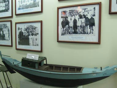 Mô hình con tàu vỏ gỗ đơn sơ 2 đáy đầu tiên của đoàn tàu không số cùng những bức ảnh về chiến sỹ trong thường phục. Mô hình con tàu vỏ gỗ đơn sơ 2 đáy đầu tiên của đoàn tàu không số cùng những bức ảnh về chiến sỹ trong thường phục