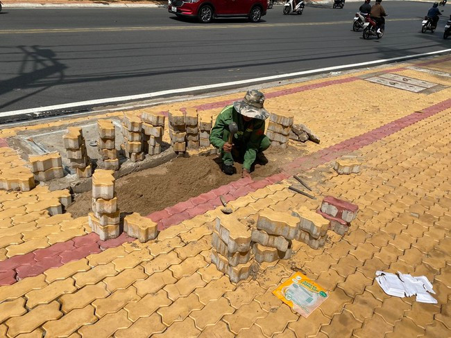 Công nhân đang khẩn trương lát lại đá vỉa hè trên đường Võ Văn Ngân bị nước gây bong tróc. Ảnh: T.Q