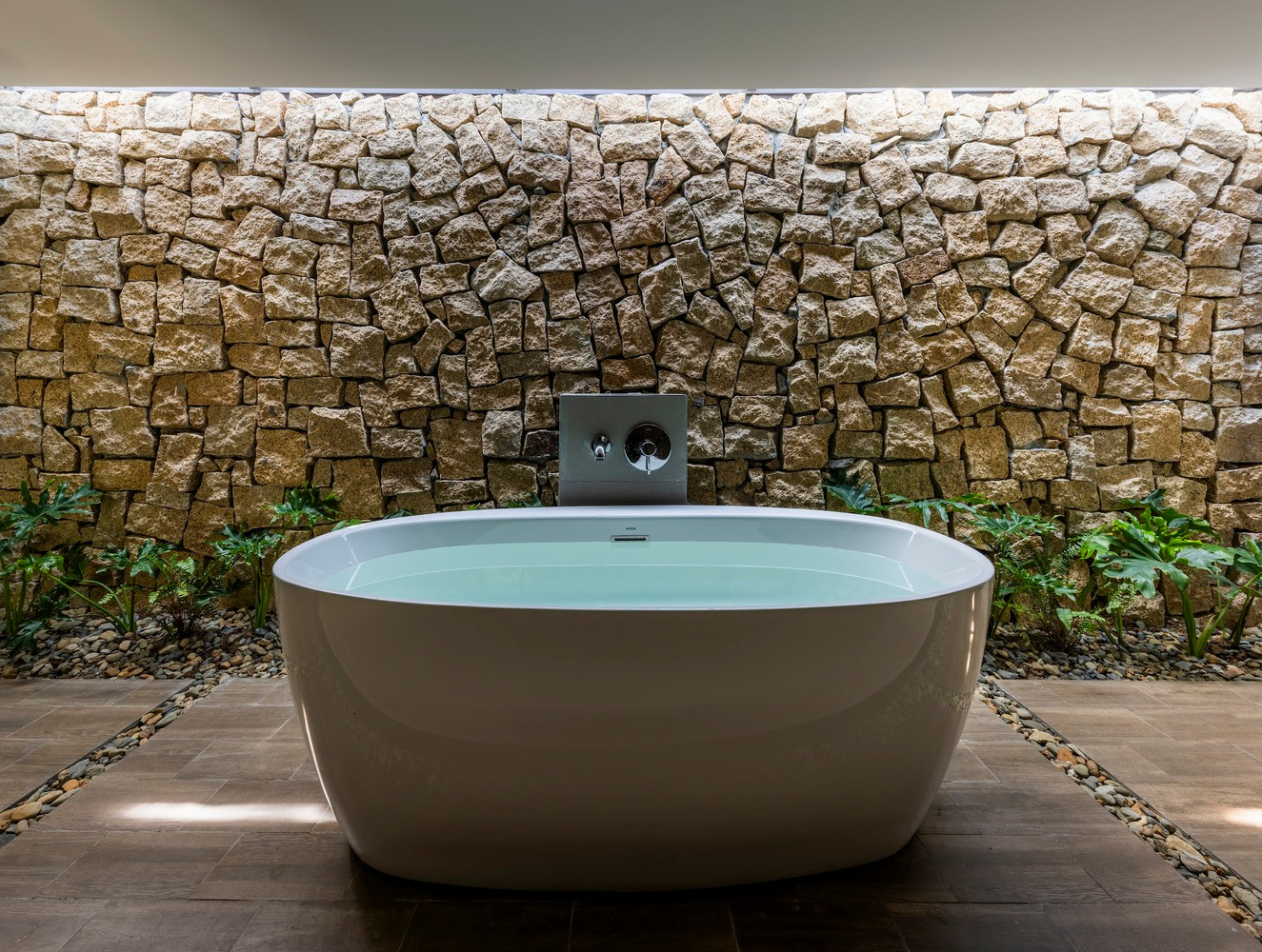 Để tăng cường kết nối với thiên nhiên, các yếu tố đá tự nhiên được kết hợp xuyên suốt, từ phòng tắm đến khu vườn, đá được sử dụng cho sàn nhà, vừa tạo thêm nét độc đáo vừa bền vững cho công trình.