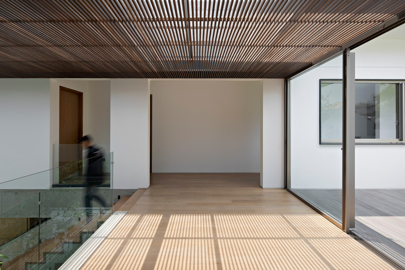 Các kiến trúc sư đã lắp đặt hai cửa trượt bằng kính, nối liền với hành lang. Điểm nhấn của hệ thống cửa này chính là khung nhôm mỏng, khi cửa mở, các khung cửa xếp khít vào nhau tạo thành một đường thẳng liền mạch, mang đến sự đồng nhất về mặt thẩm mỹ.