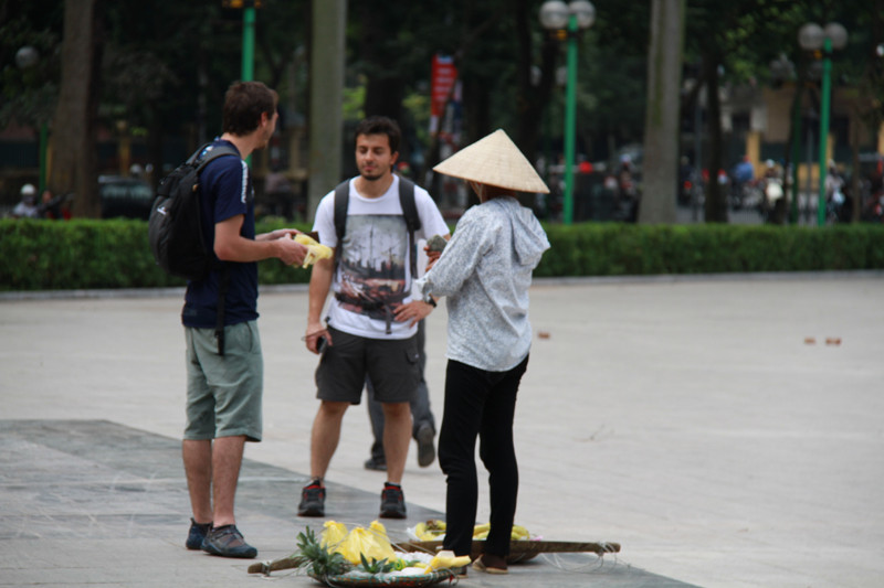 Một người bán hàng rong vẫn kiên trì đứng đợi du khách cầm túi dứa trên tay nói chuyện. Chỉ đến khi du khách này trả lại một nửa và trả tiền, người phụ nữ này mới chịu rời khỏi. Ảnh: Trường Phong
