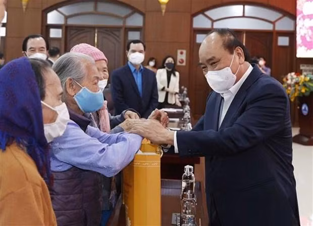 Chủ tịch nước Nguyễn Xuân Phúc trao quà Tết cho đại diện gia đình chính sách, gia đình có công với cách mạng, hộ nghèo, hộ khó khăn do bị ảnh hưởng nặng nề dịch bệnh COVID - 19, công nhân, người lao động, người bị ảnh hưởng chất độc da cam/ dioxin trên địa bàn thành phố Đà Nẵng. (Ảnh: Thống Nhất/TTXVN)