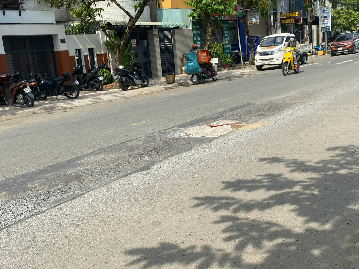 Người dân dùng cát lấp vào mặt đường bị bong tróc.