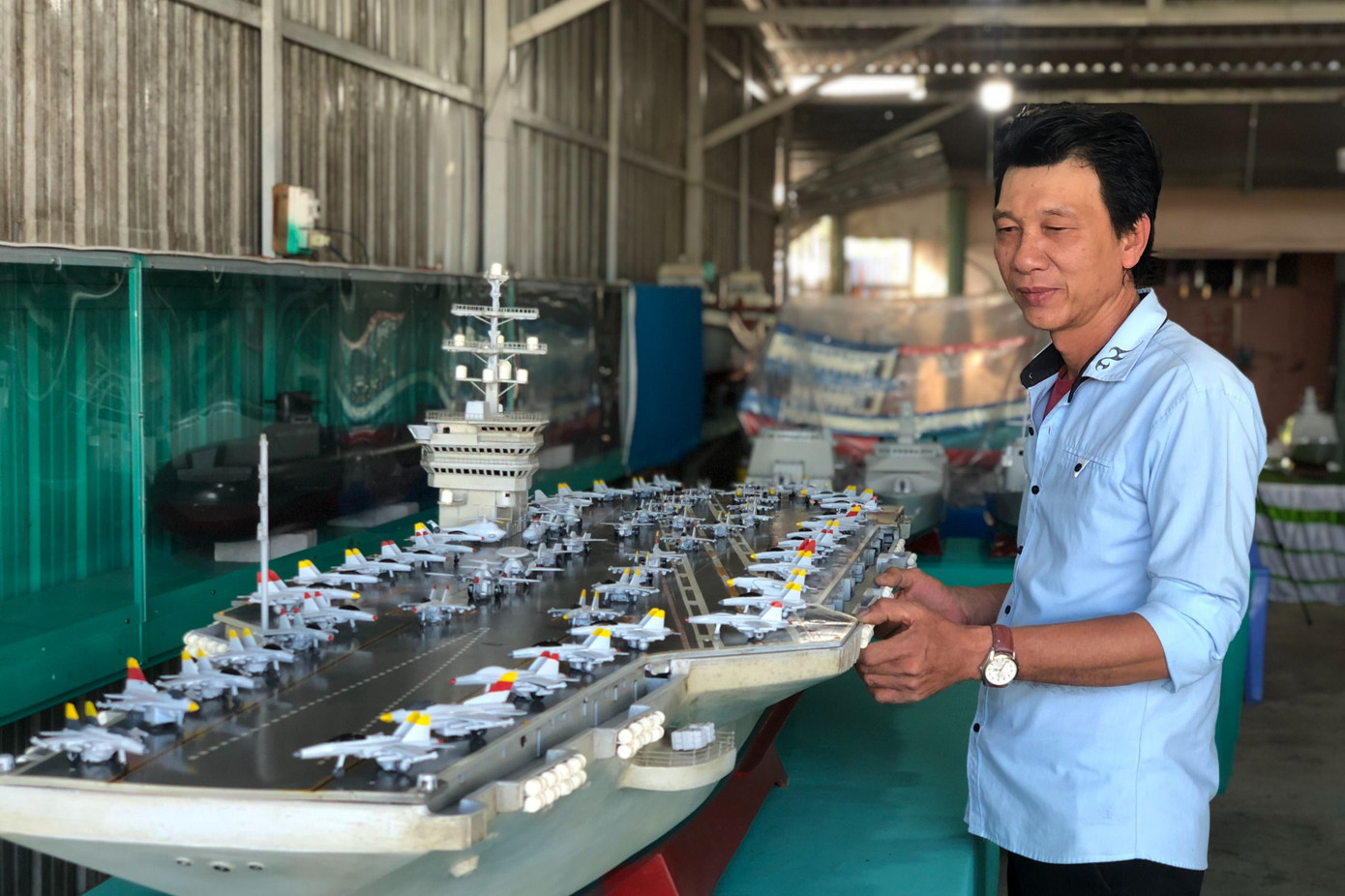 Ông Nguyễn Phương Đệ bên những mô hình tàu chiến, tàu sân bay do mình chế tạo.