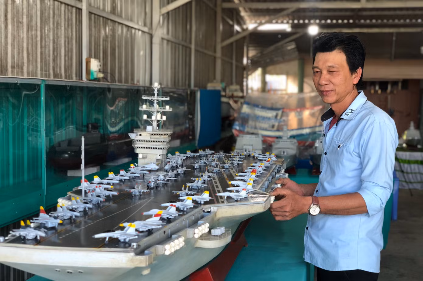 Ông Nguyễn Phương Đệ bên những mô hình tàu chiến, tàu sân bay do mình chế tạo.