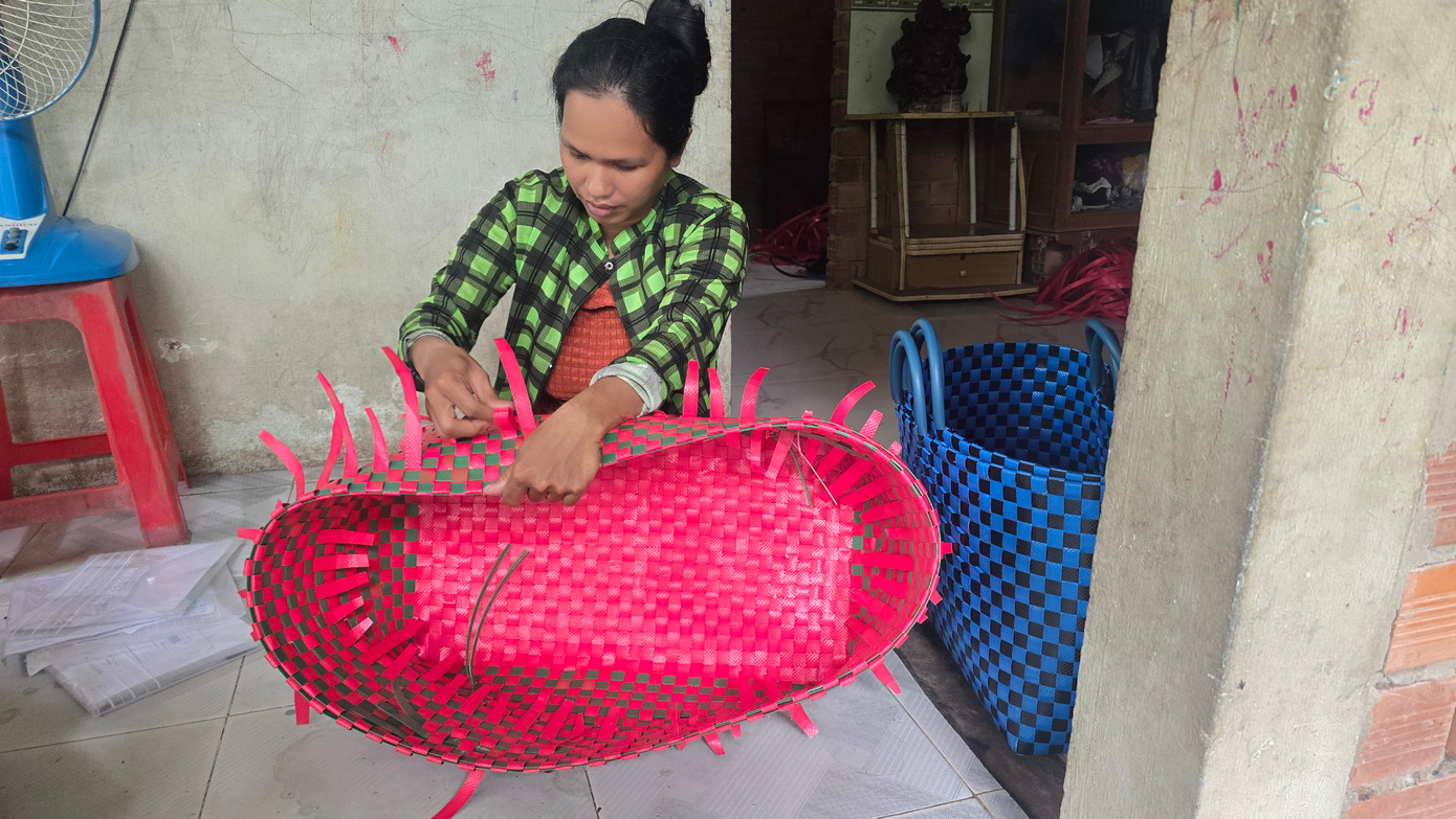 Chị Lan, mẹ cháu N. nhận thêm công việc đan giỏ ở để kiếm thêm thu nhập, vừa chăm sóc con.