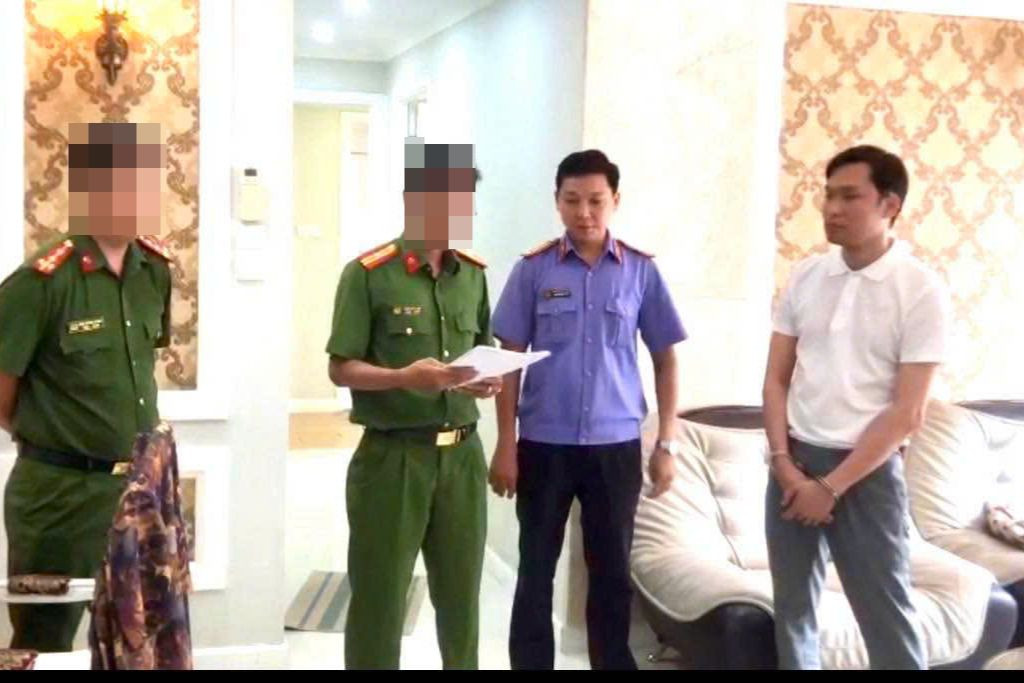 Cơ quan công an tống đạt các quyết định tố tụng đối với Tuấn (bìa phải).