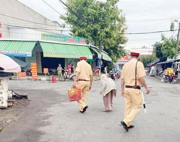 Hai cán bộ CSGT mua măng giúp cụ bà 85 tuổi rồi sau đó đưa về tận nhà. Ảnh người dân cung cấp.