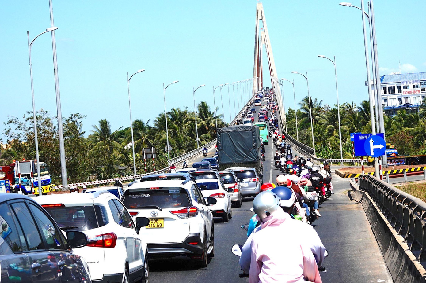 Phía Bến Tre, lượng phương tiện đổ về rất đông khiến giao thông bị ùn ứ. Nhiều xe máy chen chúc nhau qua cầu.
