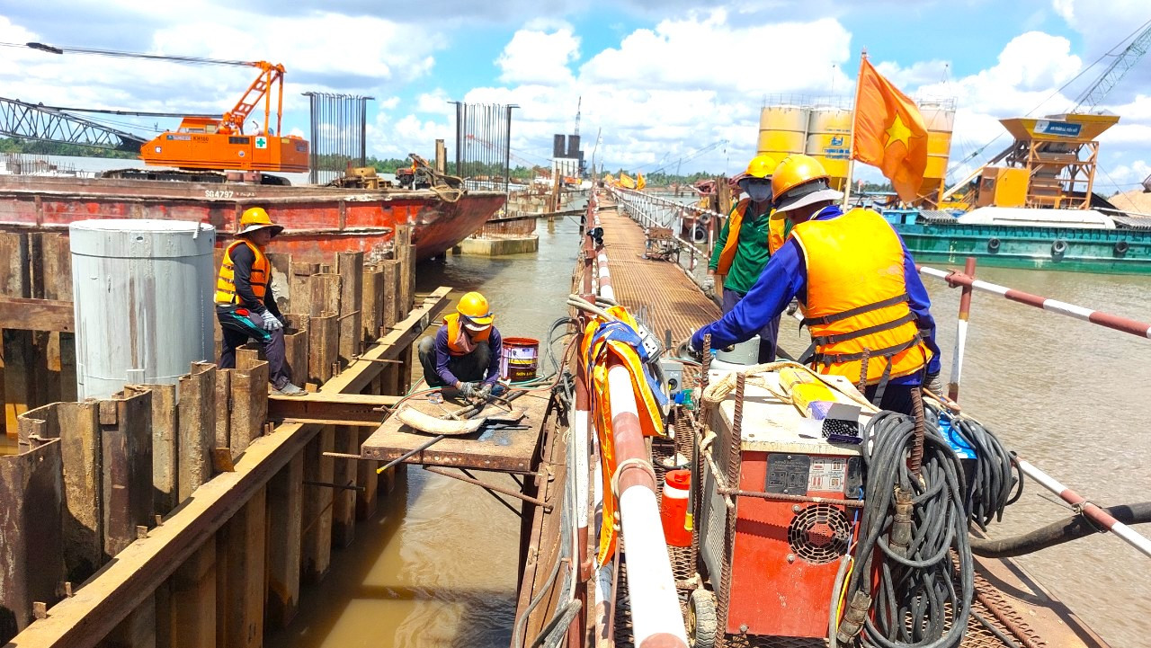 Công nhân trong bộ đồ bảo hộ vẫn miệt mài làm việc, bất chấp nắng nóng.