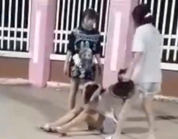 Nhóm nữ sinh dùng mũ bảo hiểm đánh vào đầu bạn ngay trước cổng trường (Ảnh cắt từ clip).