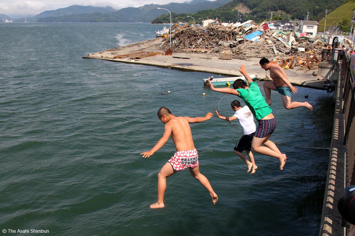 Sau giờ tan học, trên đường về nhà các em học sinh đứng trên cầu nhảy xuống biển để lặn. Ảnh chụp 01/07/2011 tại Tp. Ishinomaki, tỉnh Miyagi