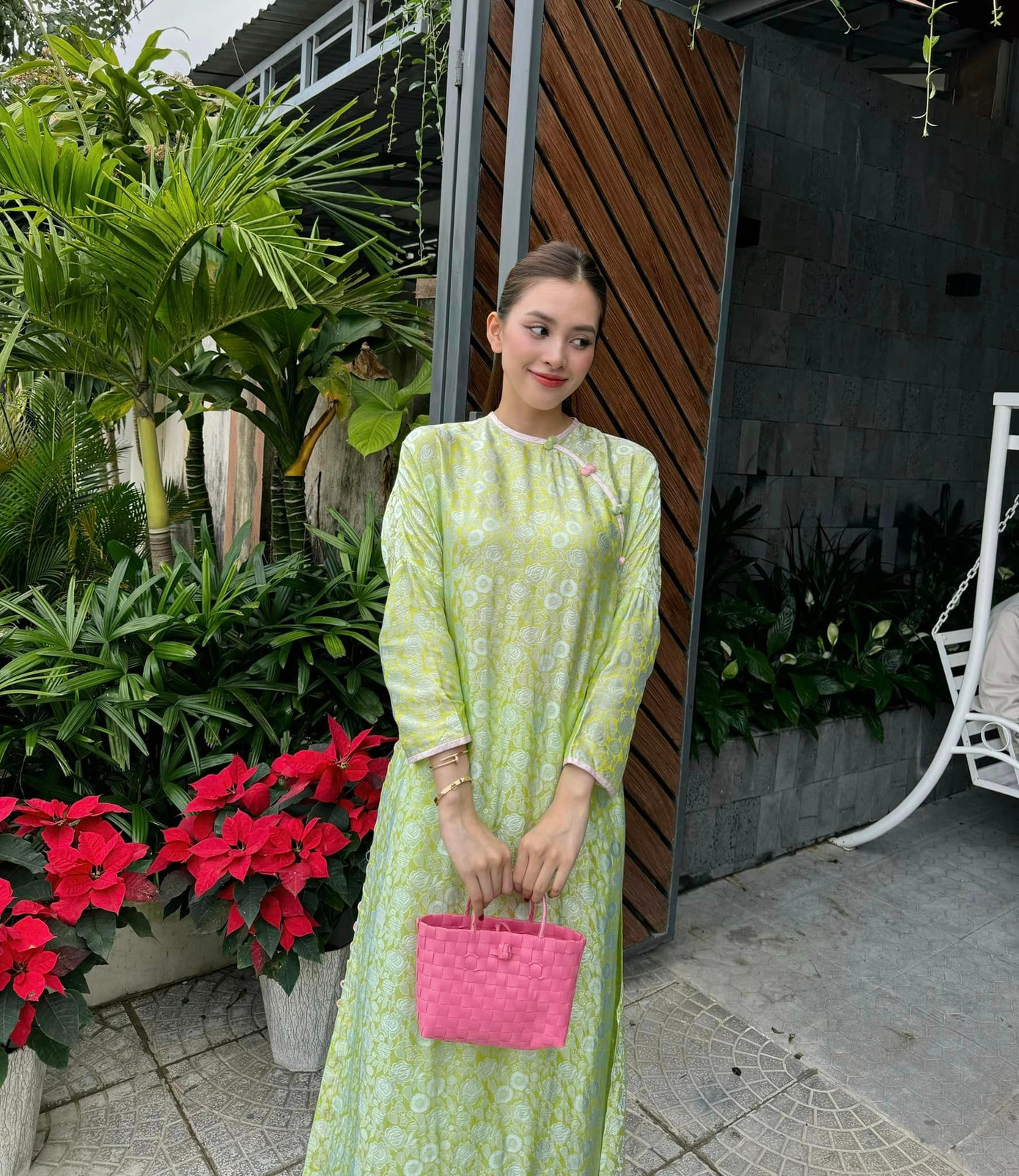 Hoa hậu Tiểu Vy diện áo dài xanh họa tiết nền nã. Cô phối cùng túi cói tông màu hồng nổi bật.