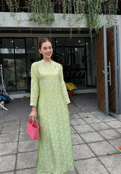 Hoa hậu Tiểu Vy diện áo dài xanh họa tiết nền nã. Cô phối cùng túi cói tông màu hồng nổi bật.