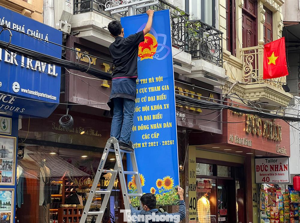 Cán bộ trung tâm văn hóa phường Hàng Gai-quận Hoàn Kiếm lắp băng rôn có dòng chữ:" Cử tri Hà Nội tích cực tham gia bầu cử Đại biểu Quốc hội khóa XV và Đại biểu Hội đồng nhân dân các cấp nhiệm kỳ 2021-2026".