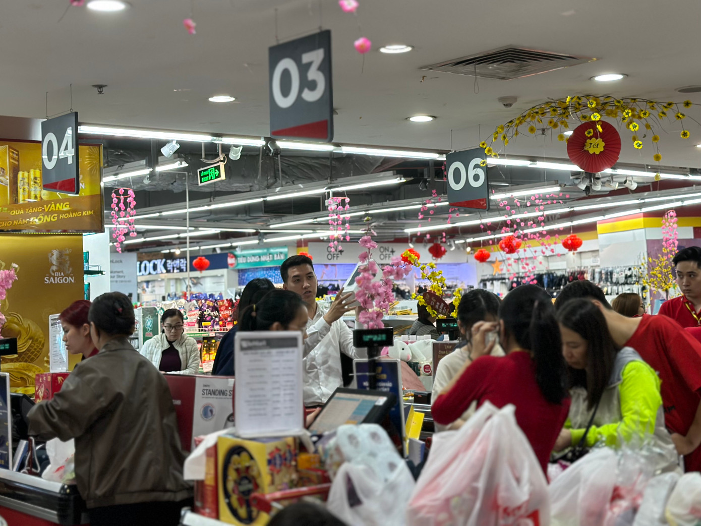 Tối 27 Tết, mất khoảng 20 phút xếp hàng tại một siêu thị trên đường Phạm Ngọc Thạch (quận Đống Đa), vợ chồng chị Quỳnh Phương mới thanh toán xong giỏ hàng Tết gồm nước ngọt, bia, bánh kẹo, đồ ăn lẩu, và một số chất tẩy rửa. Dù vậy, chị Phương không quá sốt ruột và cho rằng việc tính toán sắm Tết thời điểm này còn hợp lý hơn nhiều so với cuối tuần trước. Như những gì diễn ra vào chủ nhật vừa qua, một số đồng nghiệp kể với chị Phương, họ mất 30 - 40 phút xếp hàng thanh toán tại siêu thị.