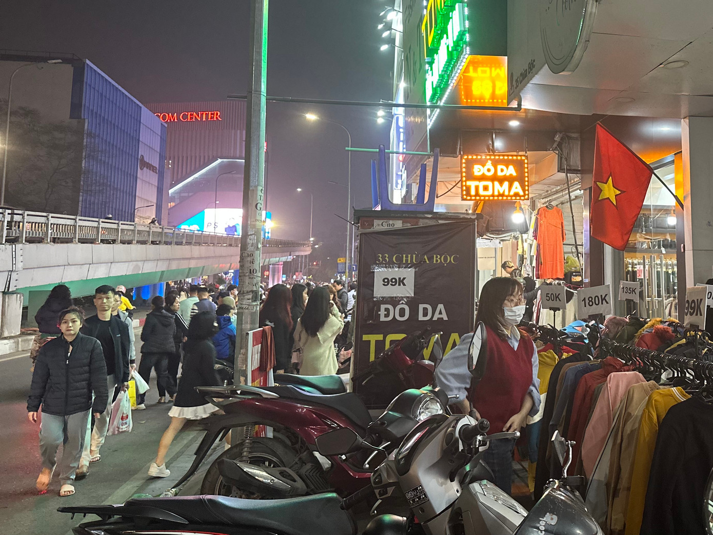 Bên ngoài cửa hàng, xe máy để kín vỉa hè, người đi bộ, dạo phố sắm Tết buộc phải đi xuống lòng đường. Phương tiện di chuyển qua phố Chùa Bộc (Hà Nội) tương đối khó khăn trong tối muộn 27 Tết.