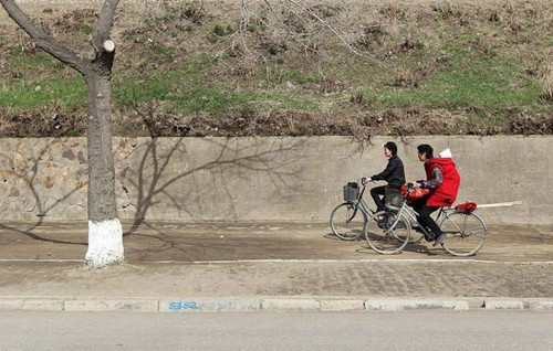 Hai người đạp xe sóng đôi trên một con đường vắng vẻ ở Rason