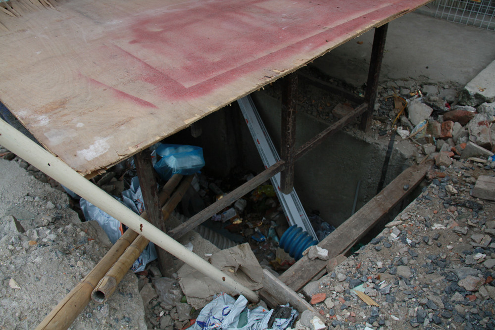 Một số người cẩn thận còn dựng đồ đạc, phủ tấm gỗ lên trên một chiếc cống chưa có nắp. Ảnh: Trường Phong