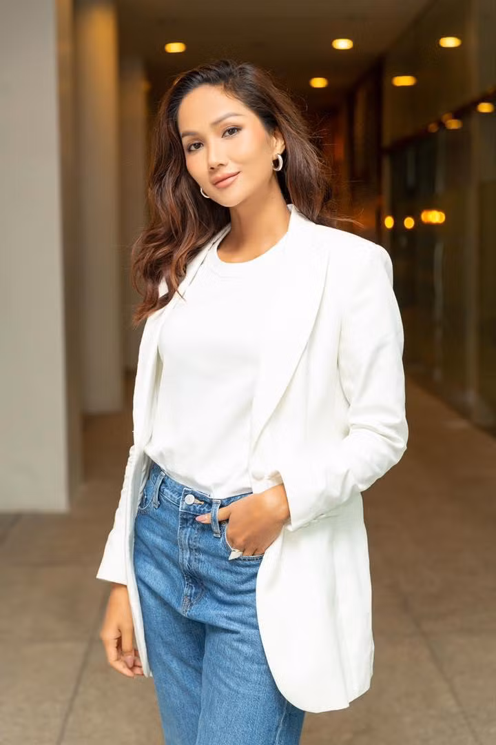 H'Hen Niê thanh lịch khi phối áo thun trắng, quần jeans với blazer trắng. H'Hen Niê thanh lịch khi phối áo thun trắng, quần jeans với blazer trắng.