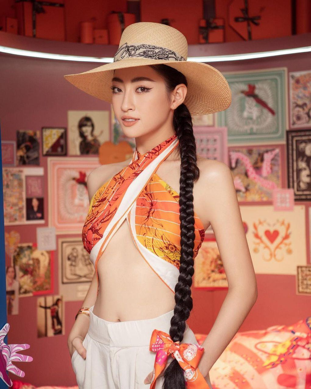 Lương Thùy Linh gây sốt khi dùng khăn lụa màu cam quấn thành áo, kết hợp với nhiều phụ kiện trang sức và mái tóc bện dài.