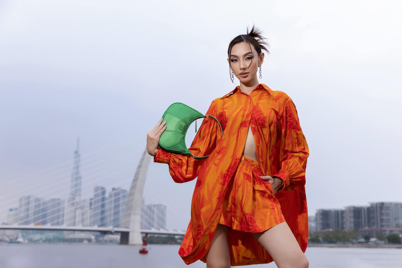 Hoa hậu Thùy Tiên chọn set quần áo màu cam, kết hợp túi xách màu xanh để khoe khéo vòng eo con kiến.