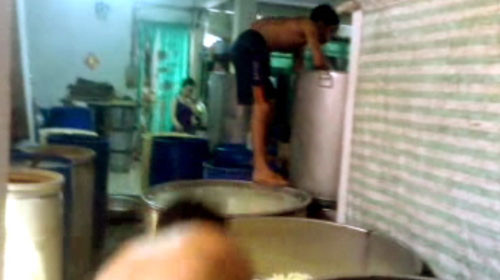 Người làm của cơ sở chế biến mứt tết T (đường Thái Phiên, Q.6) ở trần làm việc, trèo chân trần lên thùng ngâm mứt. Ảnh: Minh Trung (Tuổi Trẻ)