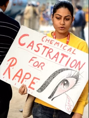 Một phụ nữ Ấn Độ mang tấm biển yêu cầu thiến dâm tặc. Ảnh: Times of India