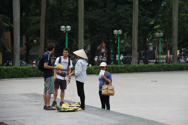Một người phụ nữ bán hàng rong dúi vào tay một du khách tây túi đựng dứa gọt sẵn. Ảnh: Trường Phong