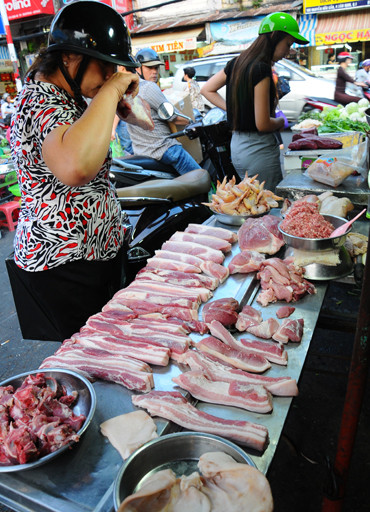 Khách hàng ngửi thịt heo trước khi mua tại chợ Tân Định (TP.HCM) chiều 9-8. Ảnh: T.T.D.. Khách hàng ngửi thịt heo trước khi mua tại chợ Tân Định (TP.HCM) chiều 9-8. Ảnh: T.T.D.