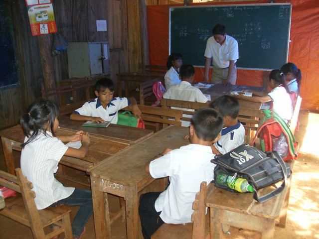 Thầy Võ Chí Thanh đang cho 4 em lớp 4 làm bài tập toán và 4 em lớp 5 học tiếng Việt