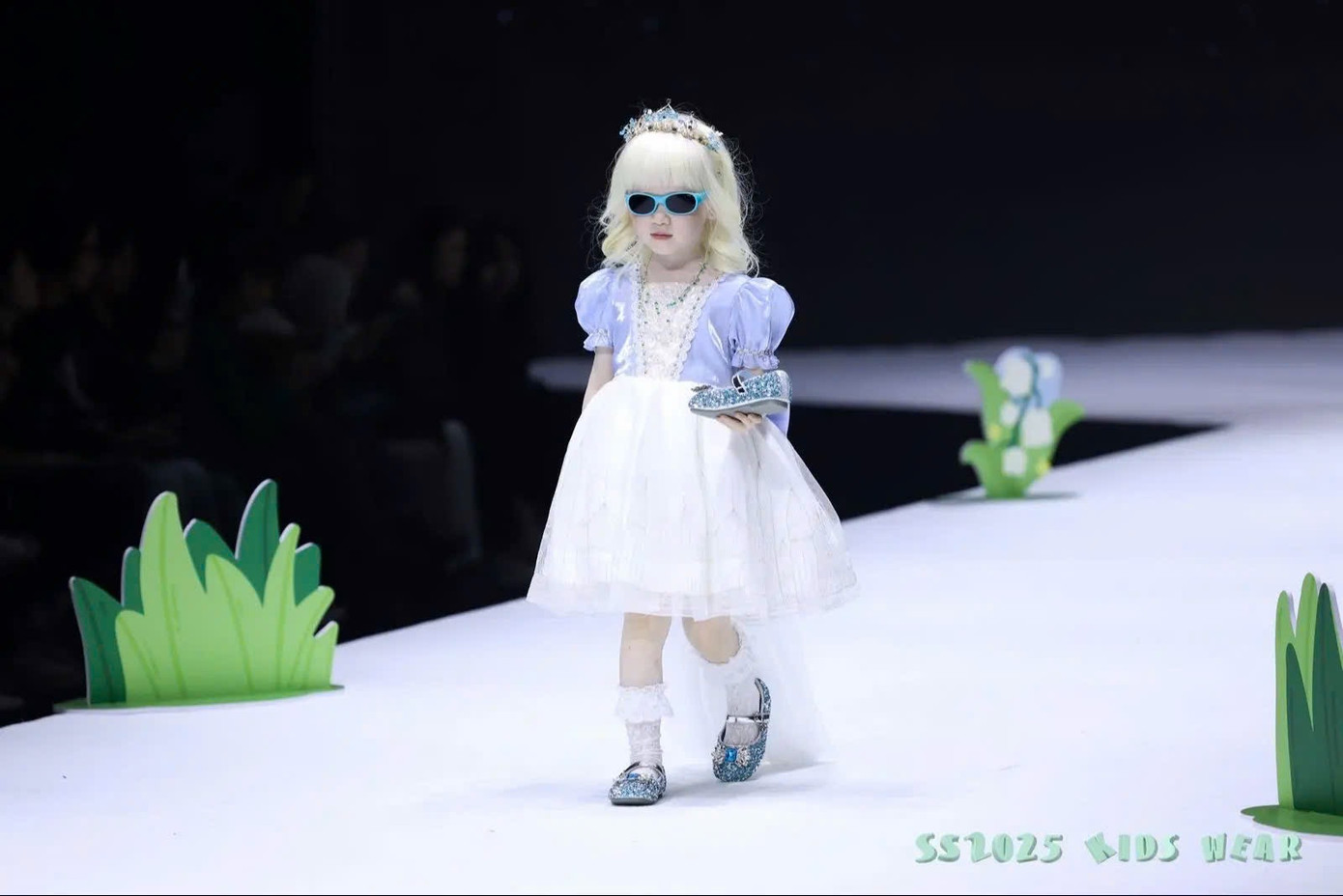 Với mái tóc trắng tự nhiên và phong thái tự tin, cô bé bước ra như công chúa Lọ Lem cầm trên tay chiếc hài nhỏ. - Ảnh: Douyin nhân vật