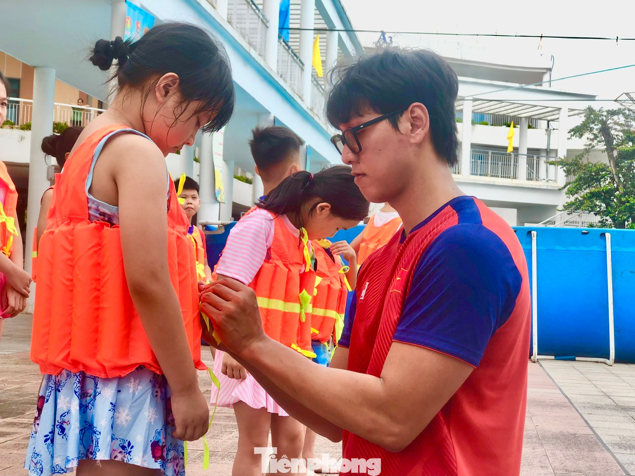 Kình ngư Hoàng Quý Phước hướng dẫn các em mặc áo bơi, khởi động trước khi xuống bể bơi Kình ngư Hoàng Quý Phước hướng dẫn các em mặc áo bơi, khởi động trước khi xuống bể bơi