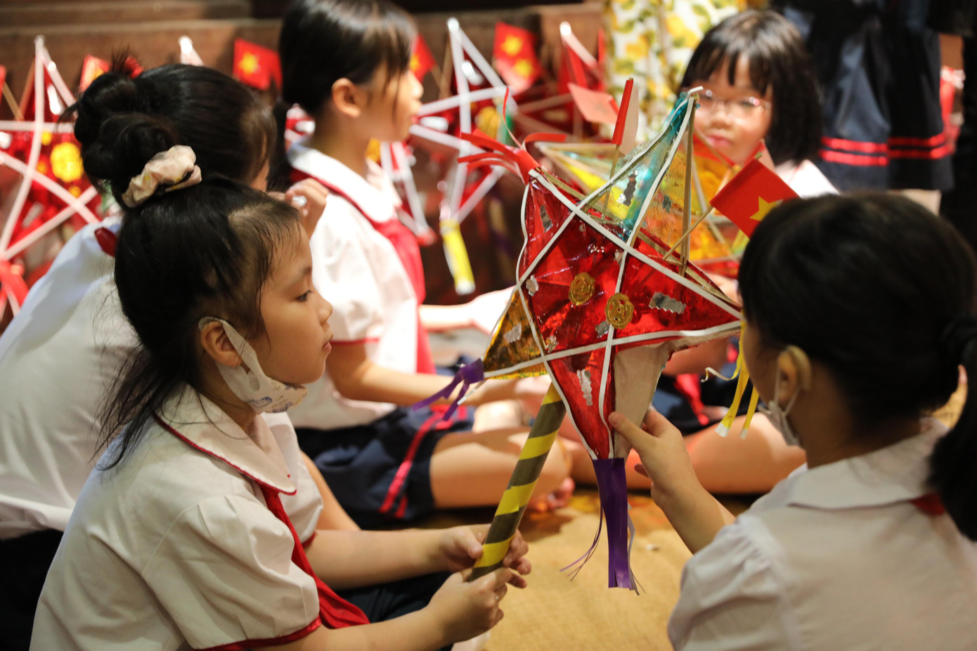 Các em học sinh chăm chú xem hướng dẫn cách làm đèn ông sao