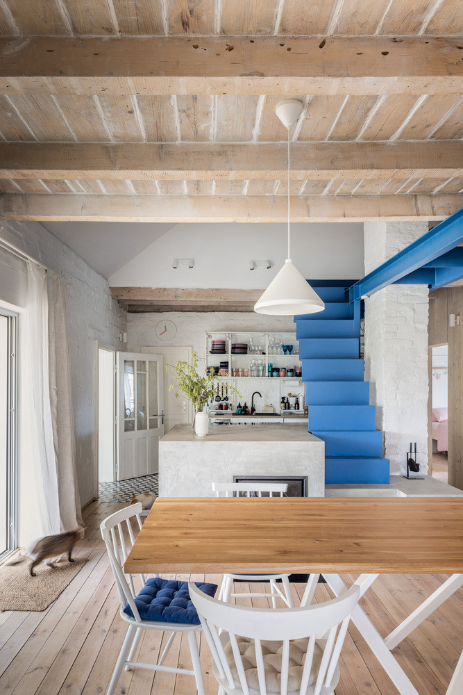 Ngôi nhà sử dụng màu sắc chủ đạo là trắng, kết hợp với nội thất bằng gỗ, kết hợp với chiếc cầu thang sắt màu xanh làm điểm nhấn.